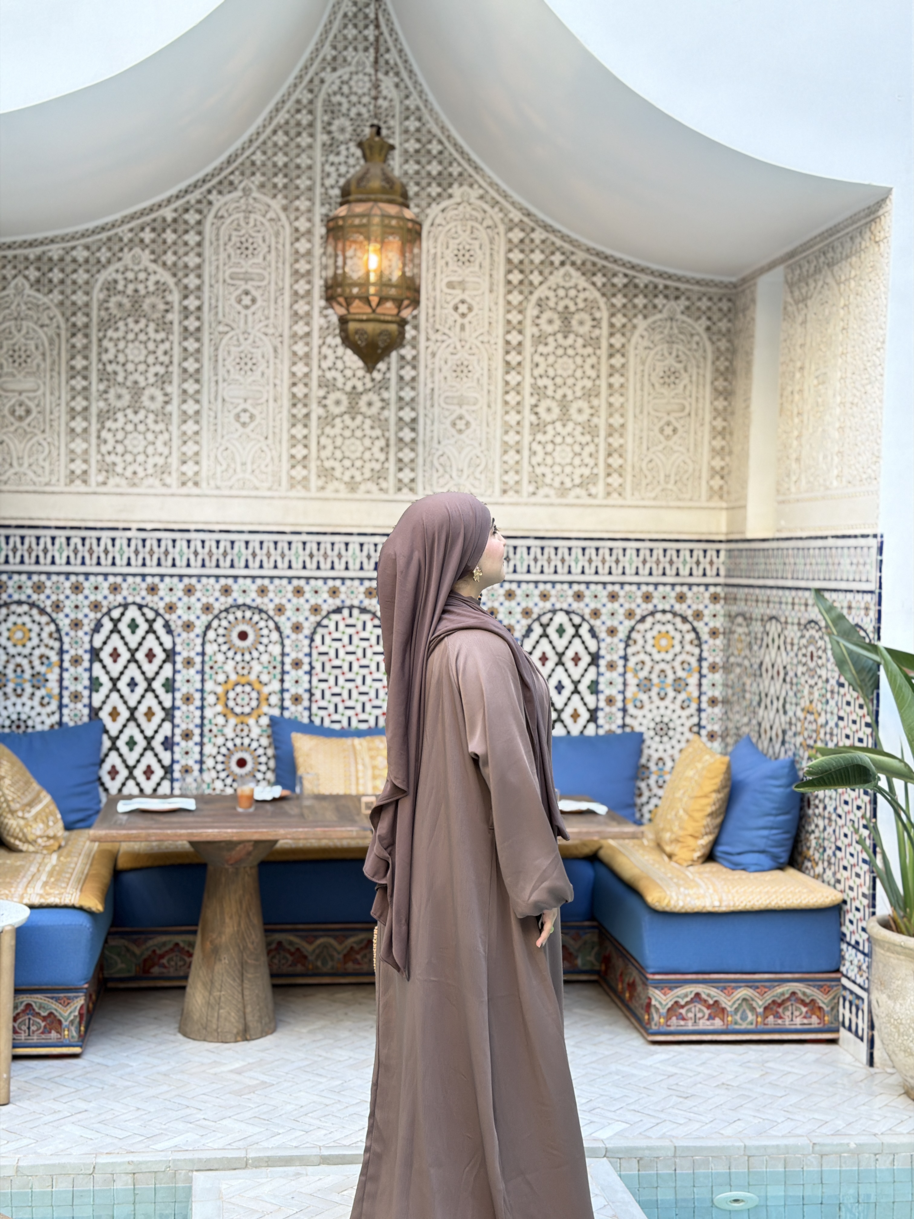 Mannequin en abaya moka dans un riad marocain orné de zellige